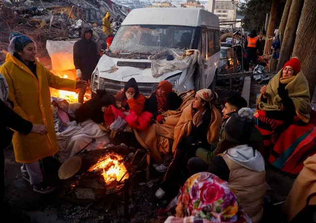 People rest around a fire next to rubble and damages near the site of a collapsed building in the aftermath of an earthquake, in Kahramanmaras, Turkey on February 8, 2023. (Photo by Suhaib Salem/Reuters)