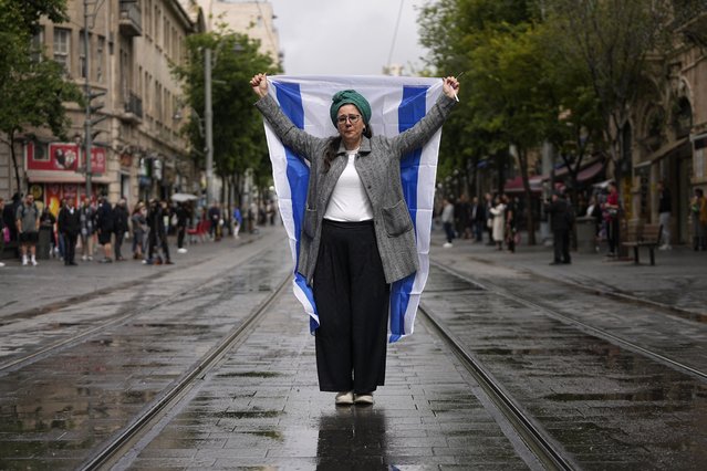 A woman stands still with an Israeli flag during a two-minute siren in memory of victims of the Holocaust, in Jerusalem, Monday, May 6, 2024. (Photo by Ohad Zwigenberg/AP Photo)
