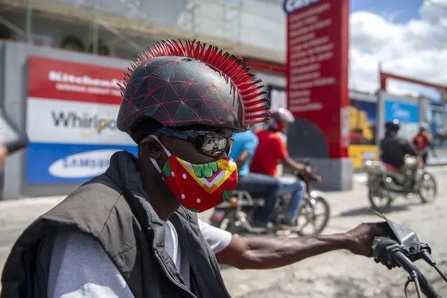 A motorcyclist wears a protective face mask and a mohawk helmet as he takes part in a protest to demand the resignation of President Jovenel Moise in Port-au-Prince, Haiti, Saturday, October 17, 2020. The country is currently experiencing a political impasse without a parliament and is now run entirely by decree under Moise. (Photo by Dieu Nalio Chery/AP Photo)