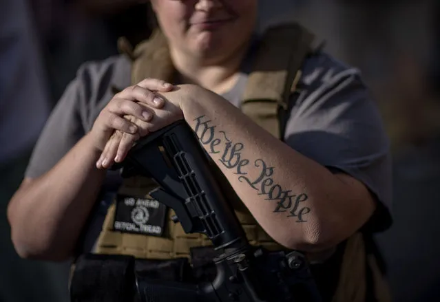 The tattoo “We The People”, a phrase from the United States Constitution, decorates the arm of Trump supporter Michelle Gregoire as she rests her hand on her gun during a protest over the election results outside the central counting board at the TFC Center in Detroit, Friday, November 6, 2020. (Photo by David Goldman/AP Photo)