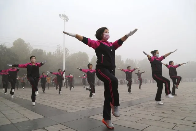 Residents wearing masks practice morning exercises on a square on a hazy day in Jiaozuo, Henan province, China, October 20, 2015. (Photo by Reuters/China Daily)