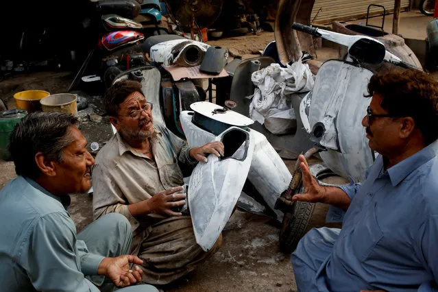 Akram (C) applies coating on Vespa scooter parts, as he chats with owners of Vespa scooters Farrukh Shahbaz (L) and Matiur Rehman outside his workshop in Karachi, Pakistan February 24, 2018. (Photo by Akhtar Soomro/Reuters)