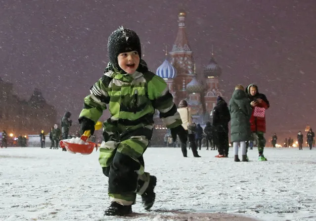 A boy plays with snow in Red Square in Moscow, Russia on November 22, 2020 after a snowstorm. Temperatures dropped below zero in the Russian capital in mid November. (Photo by Valery Sharifulin/TASS)