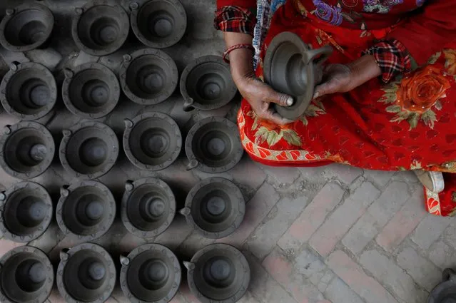 A woman makes earthenware oil lamps or “Diyo” for the upcoming festival of Tihar, also known as Diwali, in Bhaktapur, Nepal on November 8, 2020. (Photo by Navesh Chitrakar/Reuters)