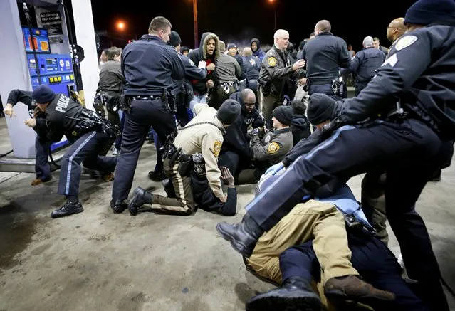 Police try to control a crowd Wednesday, December 24, 2014, on the lot of a gas station following a shooting Tuesday in Berkeley, Mo. St. Louis County police say a man who pulled a gun and pointed it at an officer has been killed. (Photo by David Carson/AP Photo/St. Louis Post-Dispatch)