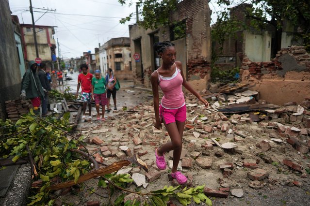 People pass by debris from a wall in the aftermath of Hurricane Melissa, in Santiago, Cuba, on October 29, 2025. (Photo by Alexandre Meneghini/Reuters)