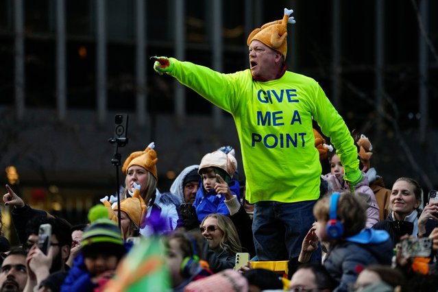A spectator motions as floats and balloons pass during the Macy's Thanksgiving Day Parade, Thursday, November 27, 2025, in New York. (Photo by Eduardo Munoz Alvarez/AP Photo)