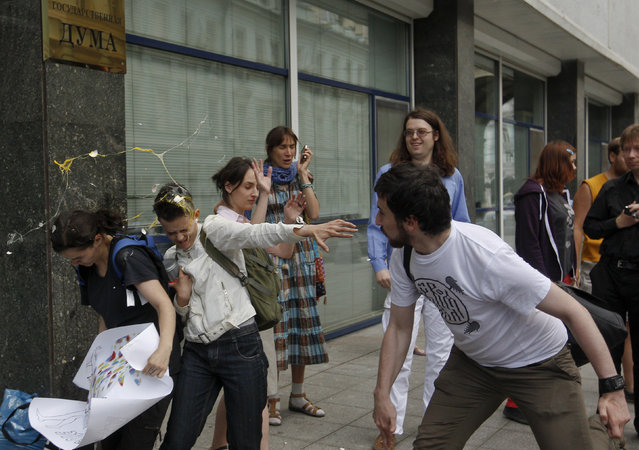 A radical Orthodox believer (R) throws an egg at gay rights activists during a protest against a proposed new law termed by the State Duma as “against advocating the rejection of traditional family values” in central Moscow June 11, 2013. Russian police detained more than 20 gay rights activists involved in a “kissing protest” on Tuesday outside parliament where lawmakers were preparing to pass a bill banning homosexual “propaganda”. (Photo by Maxim Shemetov/Reuters)