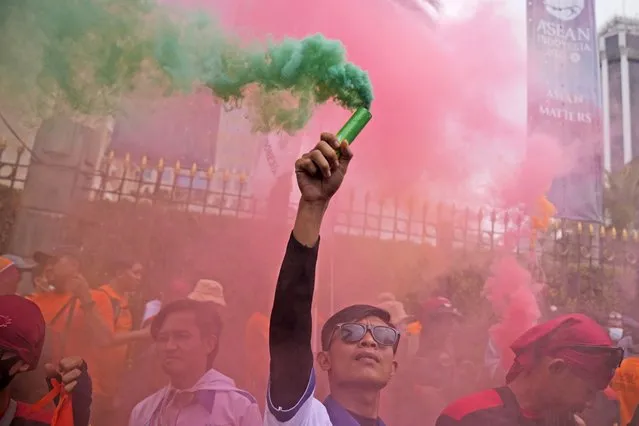 A worker holds up a smoke stick during a May Day rally in Jakarta, Indonesia, Monday, May 1, 2023. (Photo by Dita Alangkara/AP Photo)