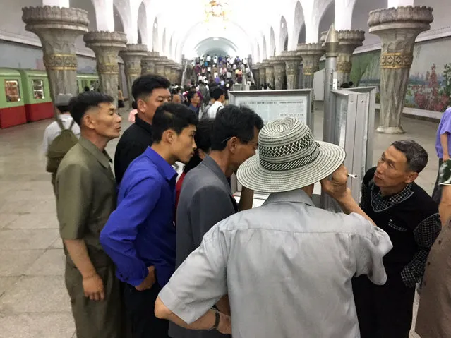 Commuters read the news of North Korean leader Kim Jong Un’s arrival in Singapore ahead of his summit with President Donald Trump at a Pyongyang subway station in Pyongyang, North Korea Monday June 11, 2018. The summit plan had received little coverage in North Korea in the months’ long lead-up, but was featured as the top story in the state run newspapers and television broadcasts a day ahead of the unprecedented meeting. (Photo by Eric Talmadge/AP Photo)