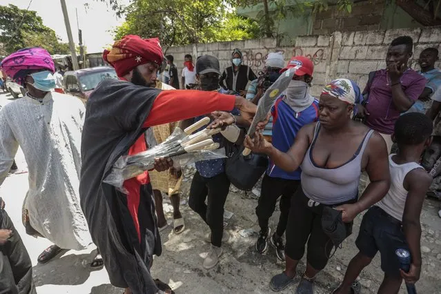 Nertil Marcelin, leader of a community group, distributes machetes to residents in an initiative to resist gangs seeking to take control of their neighborhood, in the Delmas district of Port-au-Prince, Haiti, Saturday, May 13, 2023. (Photo by Joseph Odelyn/AP Photo)