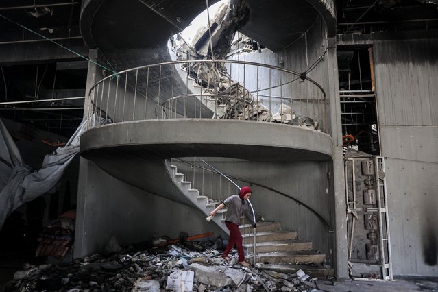 A child walks through debris towards a spiral staircase at the Gaza Municipality's Rashad al-Shawa Cultural Centre, which was heavily-damaged by Israeli bombardment, on December 11, 2024 amid the ongoing war in the Palestinian territory between Israel and Hamas. (Photo by Omar Al-Qattaa/AFP Photo)
