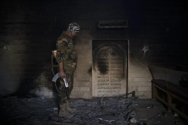A Nineveh Plain Protection Units, or NPU, fighter inspects the interior of a church damaged by Islamic State fighters during their occupation of Qaraqosh, east of Mosul, Iraq, Saturday, November 12, 2016. Qaraqosh, the biggest Christian town on the Nineveh plains in Iraq's north, fell to the Islamic State group in 2014 and was recently retaken by Iraqi government forces. (Photo by Felipe Dana/AP Photo)
