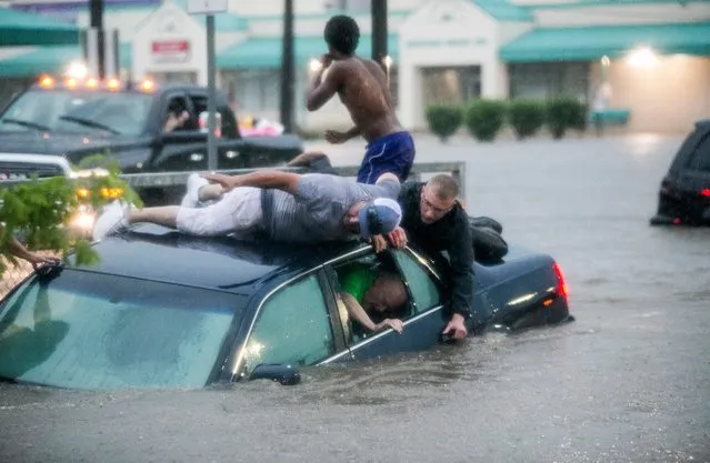 In this Monday, June 18, 2018, photo, Mark Pickett, left, and Ryan Craig, right, work to rescue Bruce Salley, who was trapped in his car by flood waters in a supermarket parking in Rockford, Ill. An evening thunderstorm brought heavy rains across the Rock River Valley causing vehicles to get stuck in flood waters and stranding motorists. (Photo by Arturo Fernandez/Rockford Register Star via AP Photo)
