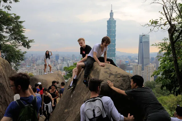 This picture taken on July 22, 2018 shows people posing on the Six Giant Rocks on Elephant Mountain in Taipei, as the Taipei 101 building is seen in the background. (Photo by Daniel Shih/AFP Photo)