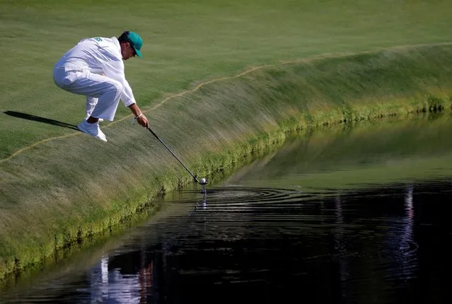 The caddie of England's Justin Rose retrieves his ball from the water on the 15th hole during a practice round at The Masters at Augusta National Golf Club in Augusta, Georgia, U.S. on April 6, 2021. (Photo by Brian Snyder/Reuters)