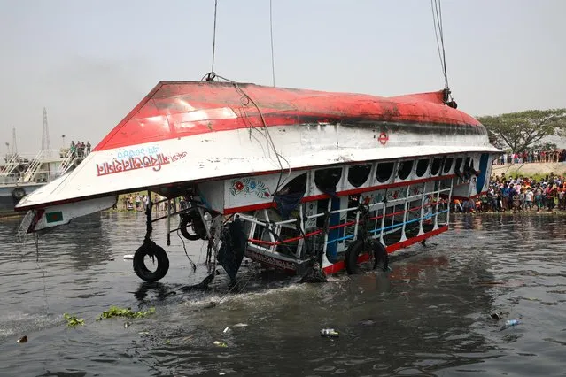 The ferry that collided with a cargo vessel and sank on Sunday in the Shitalakhsyaa River is pulled out from the river with a crane, during rescue operations in Narayanganj, Bangladesh, April 5, 2021. (Photo by Mohammad Ponir Hossain/Reuters)