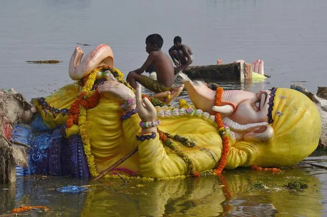 A boy sits on an idol of the Hindu elephant god Ganesh after it was immersed in the waters of Hussain Sagar lake to mark the end of 10-day-long Ganesh Chaturthi festival in the southern Indian city of Hyderabad, on September 20, 2013. (Photo by Reuters)
