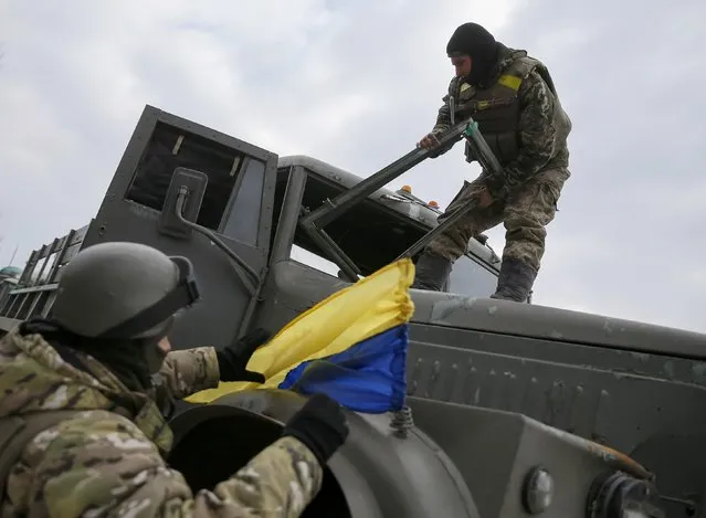 Ukrainian servicemen who fought in Debaltseve hoist a Ukrainian national flag to their vehicle before leaving for home, near Artemivsk February 19, 2015. (Photo by Gleb Garanich/Reuters)