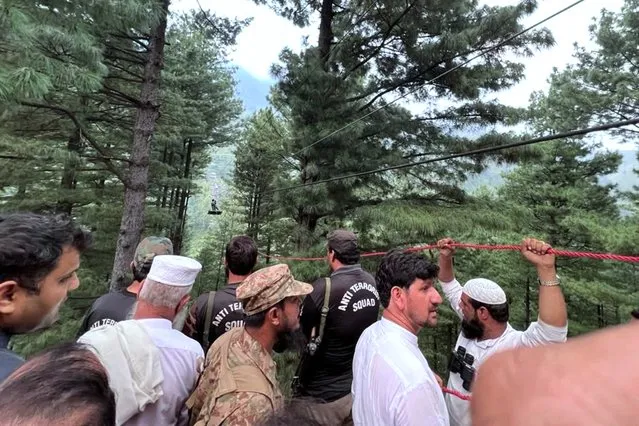 This handout photograph taken on August 22, 2023 and released by the Pakistan's Inter Service Public Relation (ISPR) shows an army soldier (top) rescueing a student survivor, who was trapped in a cable car following an incident, in Pashto village, northwestern Pakistan. Military helicopters and zipline experts rescued eight people, including six school boys, trapped for hours in a stricken cable car high above a remote Pakistan valley. (Photo by Handout/ISPR via AFP Photo)