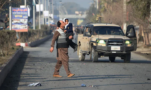 An Afghan man kisses his daughter as he walks near an attack from a building close to the Pakistan consulate in Jalalabad on January 13, 2016. (Photo by Noorullah Shirzada/AFP Photo)