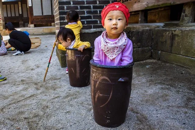 Jung Ha-yoon, 2, appears to be stuck inside a ceramic container while playing with other children at the traditional sports square during the “Taste Korea! Korean Royal Cuisine Festival” held at Unhyeon Palace in Seoul, South Korea, on October 1, 2013. (Photo by Jacquelyn Martin/Associated Press)