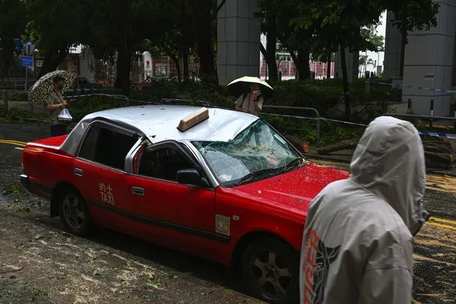 Residents look at a taxi damaged by Typhoon Saola in Chai Wan, Hong Kong, Saturday, September 2, 2023. Typhoon Saola made landfall in southern China before dawn Saturday after nearly 900,000 people were moved to safety and most of Hong Kong and other parts of coastal southern China suspended business, transport and classes. (Photo by Billy H.C. Kwok/AP Photo)