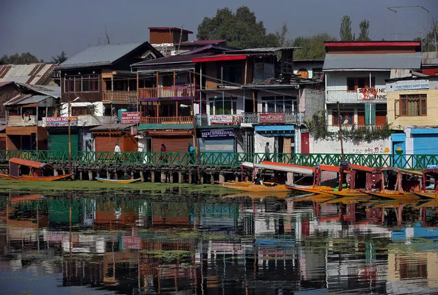 People walk on a footbridge next to houses and shops on the banks of Dal Lake in Srinagar September 26, 2018. (Photo by Danish Ismail/Reuters)