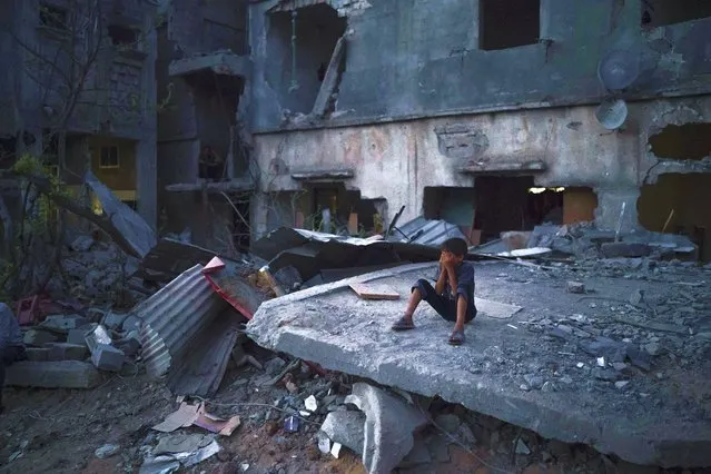 A boy closes his eyes as he plays hide-and-seek at dusk in a neighborhood heavily damaged by airstrikes during an 11-day war between Gaza's Hamas rulers and Israel, Monday, May 31, 2021 in Beit Hanoun, Gaza Strip. (Photo by Felipe Dana/AP Photo)