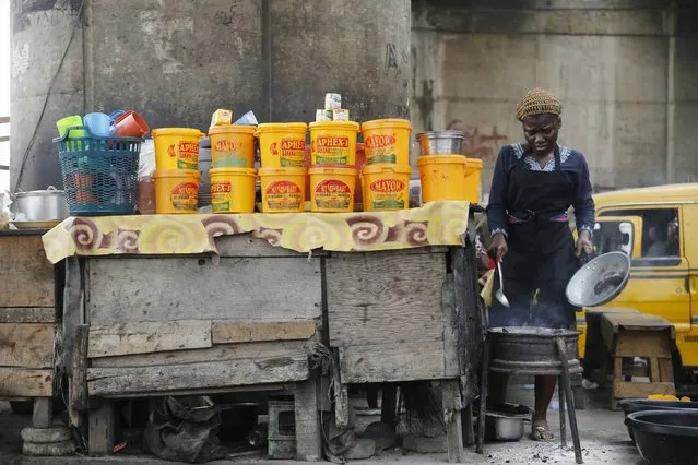 A woman makes food in a makeshift restaurant under a bridge at the Lagos central business district in Lagos February 4, 2016. (Photo by Akintunde Akinleye/Reuters)