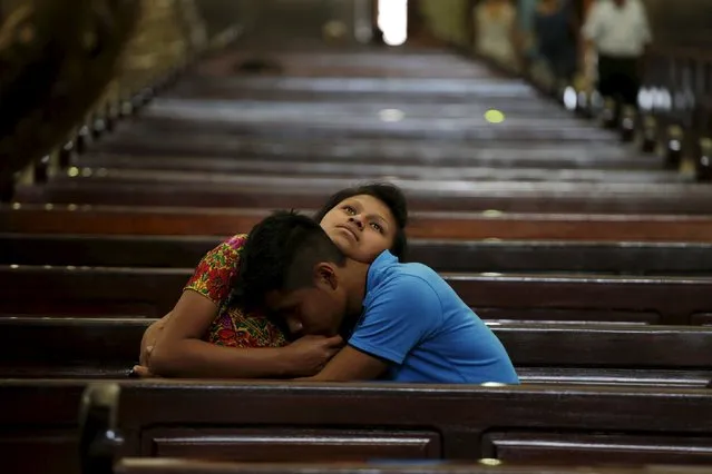A couple embrace each other while sitting in the pews of a cathedral in Guatemala City, April 1, 2015. (Photo by Jorge Dan Lopez/Reuters)