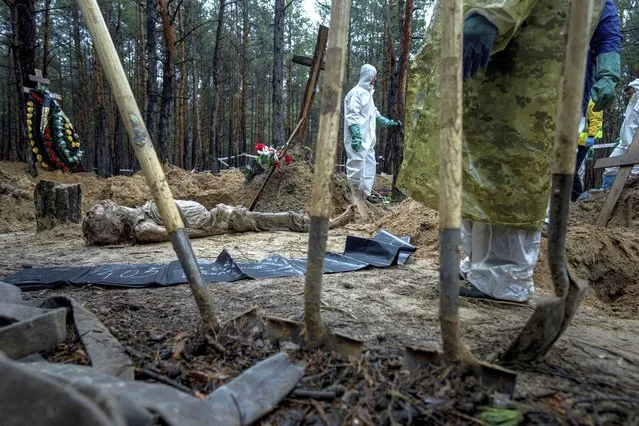 The body of a civilian lies on the ground during an exhumation in the recently retaken area of Izium, Ukraine, Friday, September 23, 2022. (Photo by Evgeniy Maloletka/AP Photo)