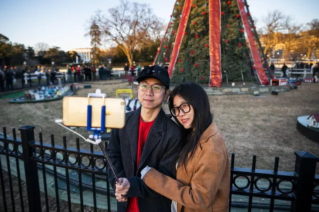 Tourists Sam (L) and Alice Wang (R) join other visitors who returned to the site of the National Christmas tree after a grant from the National Park Foundation allowed the site to reopen in President's Park, just south of the White House in Washington, DC, USA, 24 December 2018. The park had been closed to visitors due to the partial government shutdown. (Photo by Jim Lo Scalzo/EPA/EFE)