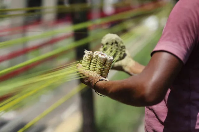 An Indian thread maker prepares colored threads for flying kites in Jammu, India, Tuesday, August 3, 2021. The demand for these threads goes up in August when people in northern India fly kites and peaks during Independence Day, which falls on August 15. (Photo by Channi Anand/AP Photo)