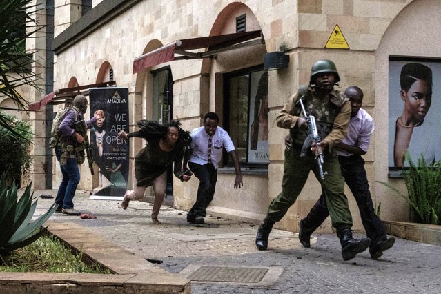 Kenyan security forces help people to escape after a bomb blast at DusitD2 hotel in Nairobi, Kenya, on January 15, 2019. A huge blast followed by a gun battle rocked an upmarket hotel and office complex in Nairobi on January 15, 2018, causing casualties, in an attack claimed by the Al-Qaeda-linked Shabaab Islamist group. (Photo by Kabir Dhanji/AFP Photo)
