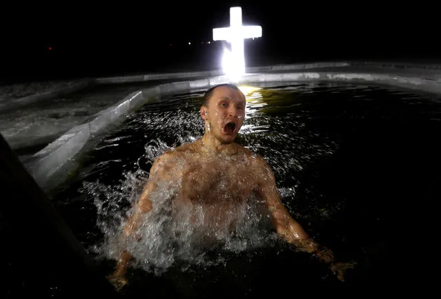 A man takes a dip in icy waters of a lake on the eve of Orthodox Epiphany in Minsk, Belarus January 18, 2019. (Photo by Vasily Fedosenko/Reuters)