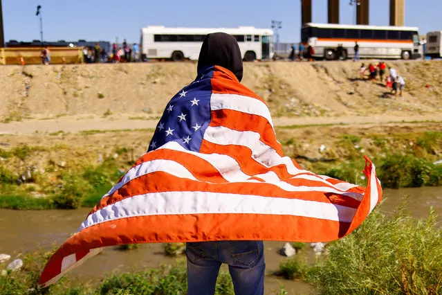 A migrant from Venezuela, who was expelled from the U.S. and sent back to Mexico under Title 42, carries a U.S. flag as he stands on the banks of the Rio Bravo river, in Ciudad Juarez, Mexico on October 26, 2022. (Photo by Jose Luis Gonzalez/Reuters)