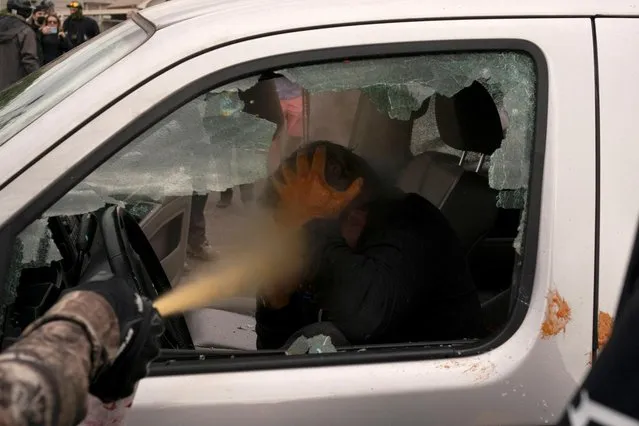 Members of the far-right Proud Boys attack a counter-protester, who is trapped in a vehicle and clutching their head, during rival rallies in Portland, Oregon, U.S., August 22, 2021. (Photo by David Ryder/Reuters)