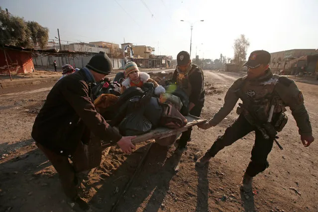 Iraqi forces help displaced people as they flee during a battle with Islamic State militants, in the al-Zuhoor neighborhood of Mosul, Iraq, January 8, 2017. (Photo by Azad Lashkari/Reuters)