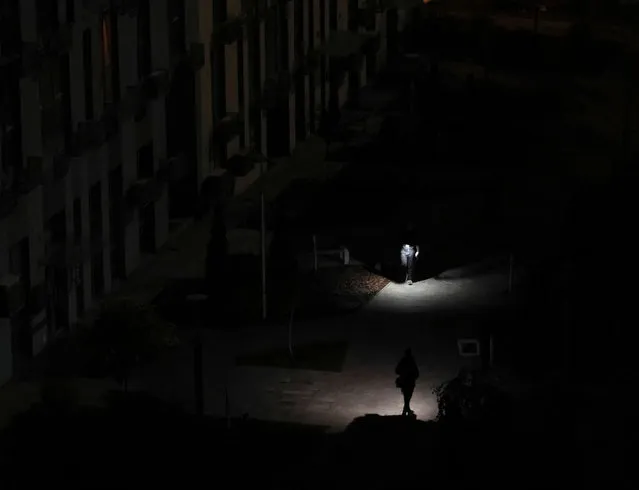 Local residents light their way when they walk in an yard of an apartment building during a power outage after critical civil infrastructure was hit by a Russian missile attacks in Ukraine, as Russia's invasion of Ukraine continues, in Kyiv, Ukraine on November 9, 2022. (Photo by Gleb Garanich/Reuters)