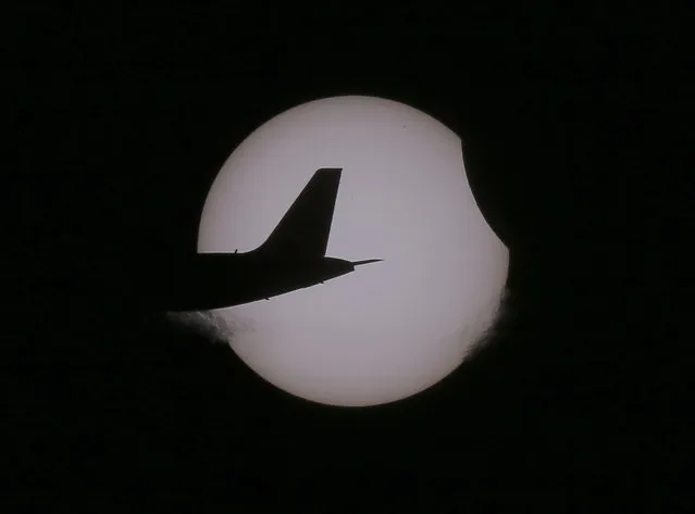 An Air Asia passenger plane flies as a partial solar eclipse occurs Wednesday, March 9, 2016 as seen from Taguig city, east of Manila, Philippines. The rare astronomical phenomenon of total solar eclipse was witnessed in Indonesia on Wednesday along a narrow path that stretched across 12 provinces encompassing three time zones and about 40 million people. In other parts of the Indonesian archipelago and Asia, a partial eclipse was visible. (Photo by Bullit Marquez/AP Photo)