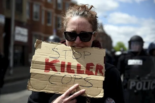A protester holds a sign with her mouth to keep her hands free near the CVS Pharmacy building on Pennsylvania Avenue in Baltimore April 28, 2015. (Photo by Sait Serkan Gurbuz/Reuters)