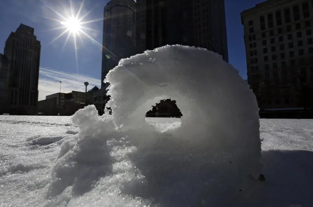 A snowroll appears on the statehouse lawn in Columbus, Ohio, Monday, January 27, 2014. According to the National Weather Service, a snow roller is a rare meteorological phenomenon in which large snowballs are formed naturally when chunks of snow are blown along the ground by wind. (Photo by Tom Dodge/AP Photo/The Columbus Dispatch)