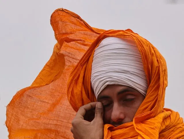 A man cleans his eye as dust blows on a windy day as farmers march towards New Delhi to press for better crop prices promised to them in 2021, at Shambhu Barrier, a border crossing between Punjab and Haryana states, India on February 19, 2024. (Photo by Francis Mascarenhas/Reuters)