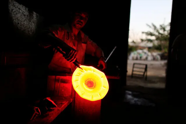A glassmaker forms molten glass next to a furnace at Cespedes factory in Olocuilta, El Salvador February 8, 2017. (Photo by Jose Cabezas/Reuters)