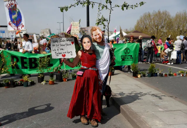 Climate change activists display a sign while wearing masks depicting Britian's Prince Harry and Meghan, Duchess of Sussex during the Extinction Rebellion protest at Waterloo Bridge in London, Britain April 18, 2019. (Photo by Peter Nicholls/Reuters)