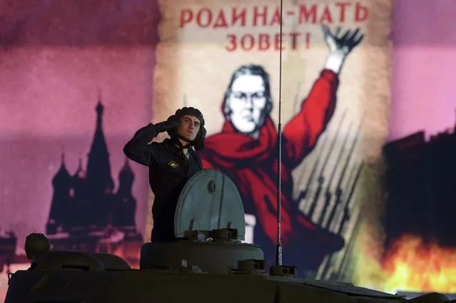 A Russian serviceman salutes as he rides a T-34 Soviet-made tank during a festive concert marking the 70th anniversary of the end of World War Two in Europe, at Red Square in Moscow, Russia, May 9, 2015. (Photo by Reuters/Host Photo Agency/RIA Novosti)