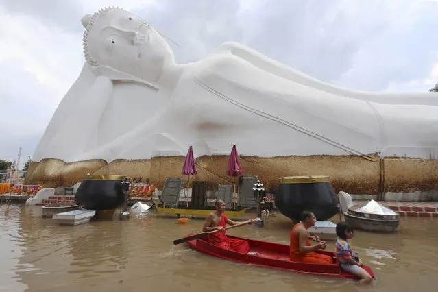 Buddhist monks paddle a boat through floodwaters in front of a reclining Buddha at the Wat Satue in Ayutthaya province north of Bangkok, Thailand, Monday, October 4, 2021. Officials in Thailand expressed optimism Monday that widespread flooding is easing, with signs that the capital, Bangkok, may be spared serious damage. (Photo by Nathathida Adireksarn/AP Photo)