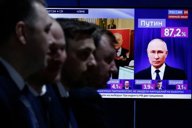 Men sit near a TV broadcasting news on the results of Russian presidential candidate and incumbent President Vladimir Putin, on the final day of the presidential election in Moscow, Russia, on March 17, 2024. (Photo by Maxim Shemetov/Reuters)
