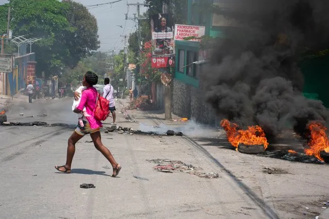 A woman carrying a child runs from the area after gunshots were heard in Port-au-Prince, Haiti, on March 20, 2024. Negotiations to form a transitional council to govern Haiti advanced on March 20, as the United States airlifted more citizens to safety from gang violence that has plunged the impoverished country into chaos. (Photo by Clarens Siffroy/AFP Photo)